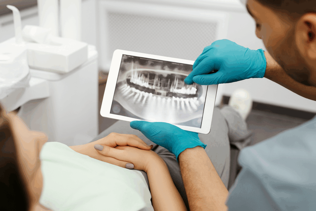 Zahnarzt zeigt Röntgenaufnahme auf Tablet